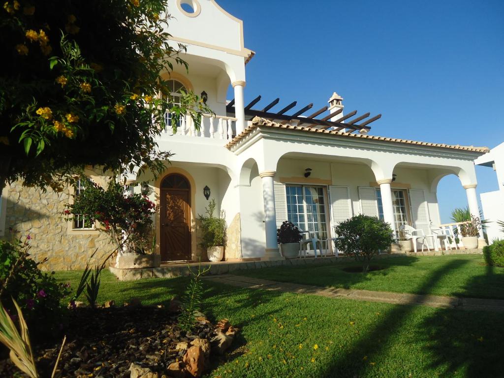 una casa blanca con un patio verde en VIVENDA L'OLIVIER, en Quarteira