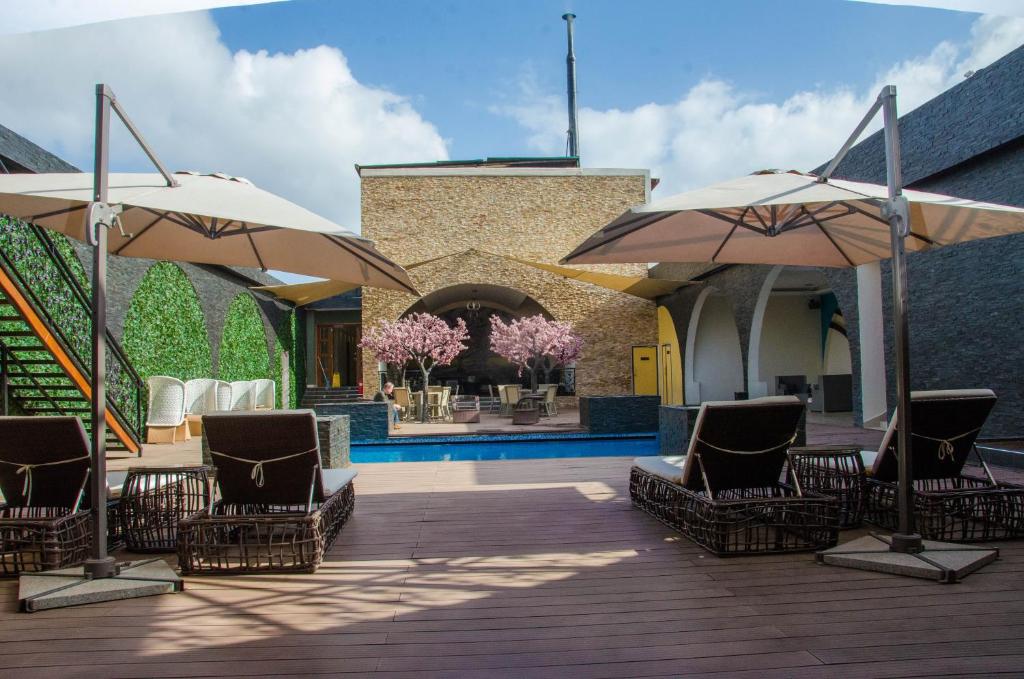 une terrasse avec des chaises et des parasols, ainsi qu'une piscine dans l'établissement Best Western Plus Meridian Hotel, à Nairobi