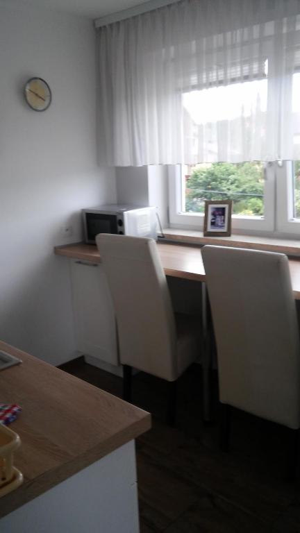 a kitchen with a desk with white chairs and a window at Apartamenty Pod Telegrafem in Kielce