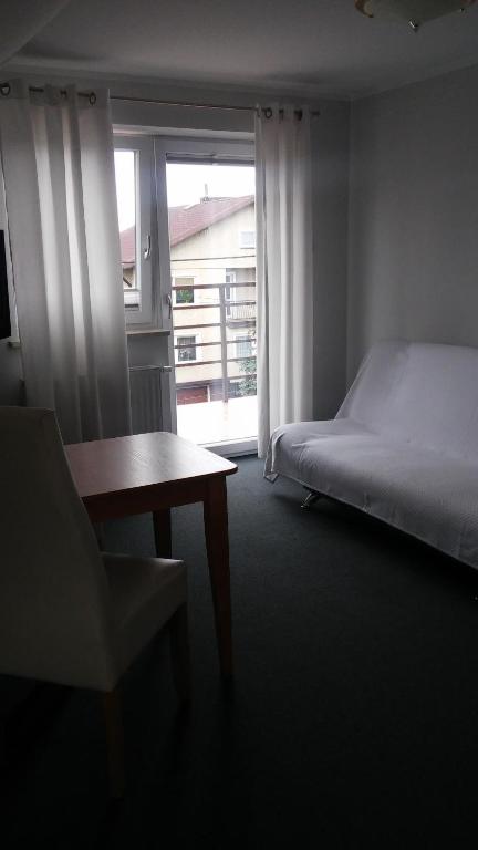 a bedroom with a bed and a chair and a window at Apartamenty Pod Telegrafem in Kielce