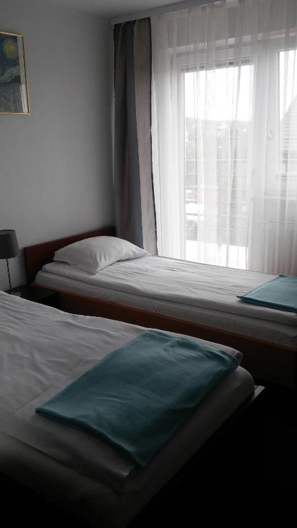 two beds in a room with a window at Apartamenty Pod Telegrafem in Kielce