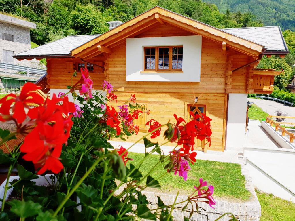 une cabane en rondins avec des fleurs devant elle dans l'établissement Casa Vacanza in tipico Chalet di montagna, à Varzo