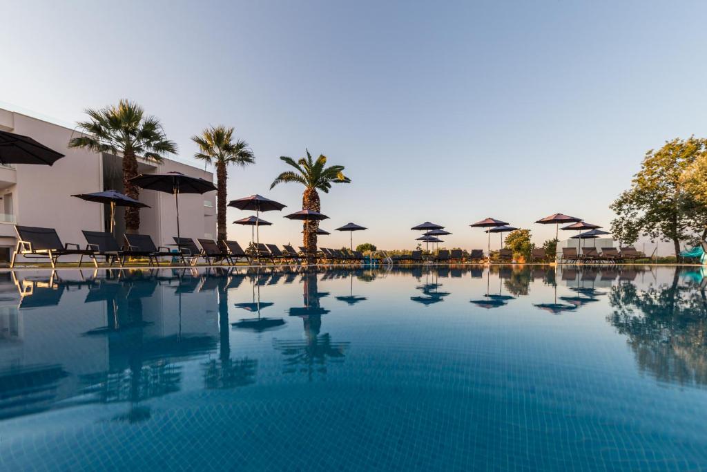 uma grande piscina com guarda-sóis e cadeiras em Mythic Summer Hotel em Paralia Katerinis