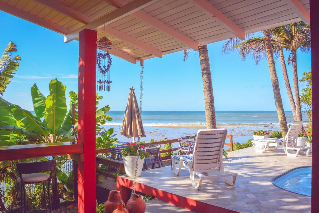 a patio with chairs and an umbrella and the beach at Pousada Canto da Brava in Balneário Camboriú