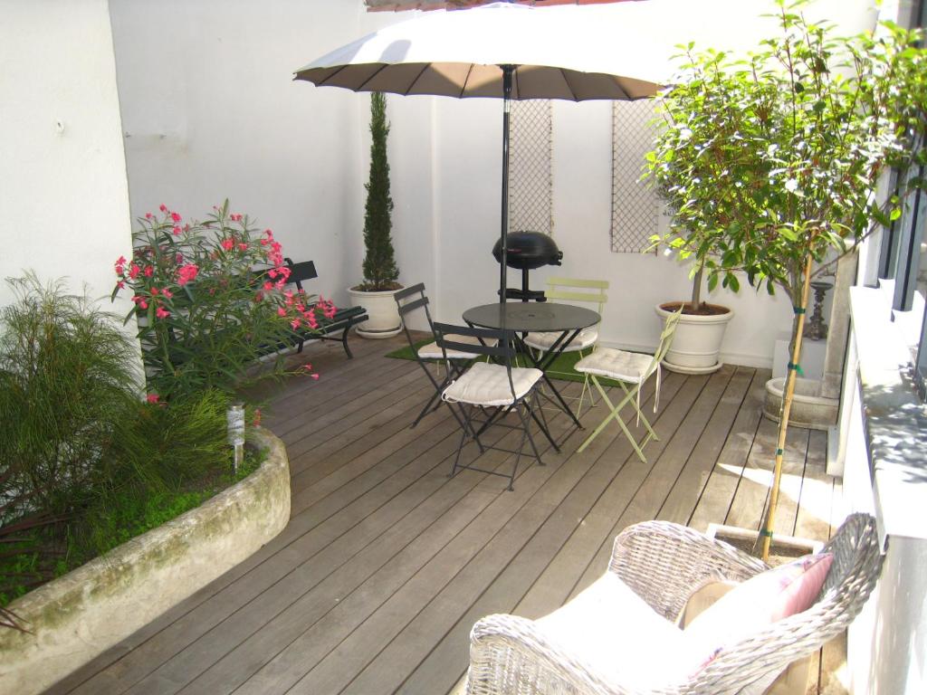 eine Terrasse mit einem Tisch, Stühlen und einem Sonnenschirm in der Unterkunft StellaHome - La petite cour in Sanary-sur-Mer