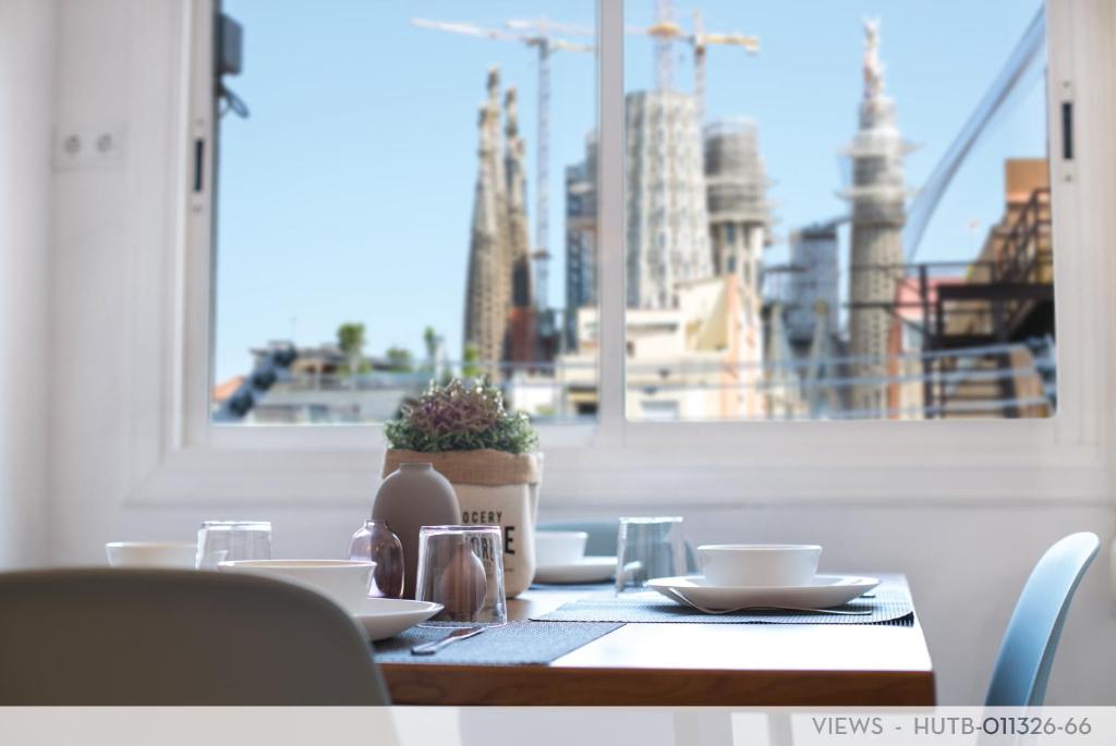 a table with dishes and a plant on it with a window at Suite Place Barcelona Còrsega in Barcelona