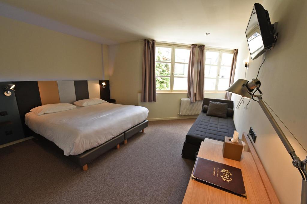 a bedroom with a bed and a couch and a television at Cit'Hotel De Harlay in Compiègne