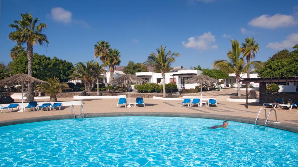 una persona en una piscina en un complejo en Bungalows Playa Limones, en Playa Blanca