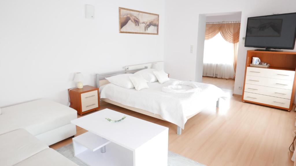 Motel Za Miedzą في Bralin: غرفة معيشة بيضاء مع سرير وتلفزيون