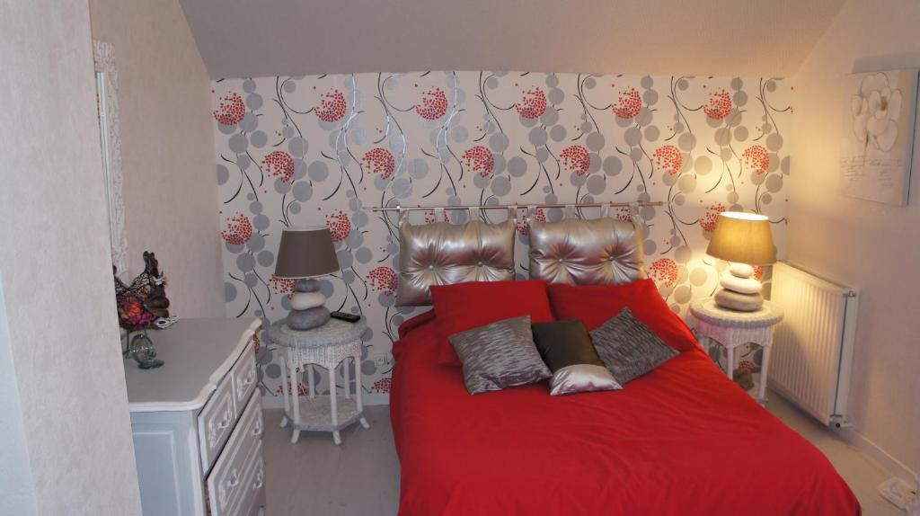 a bedroom with a red bed with two lamps at La petite maison - L'Ouche Charlot in Maux