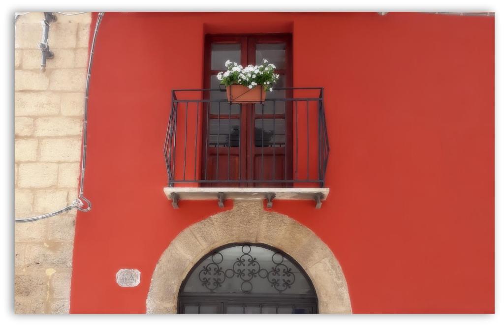 a red building with a window with a flower pot on a balcony at Casa Giavada Steripinto in Sciacca