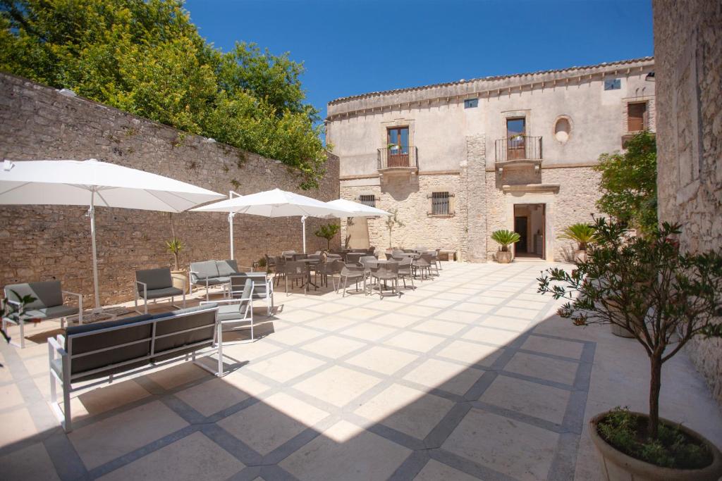 um pátio com mesas e guarda-sóis em frente a um edifício em Il Carmine Dimora Storica em Erice