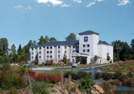 a large white building in the middle of a garden at Baymont by Wyndham Mooresville in Mooresville