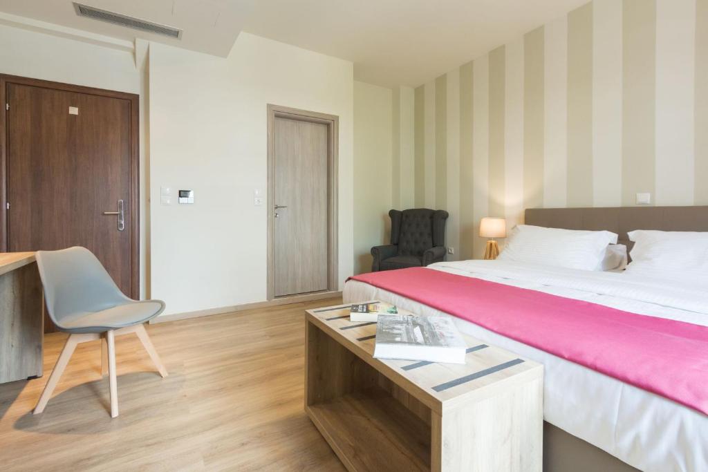 a bedroom with a bed, desk, chair, and a dresser at Hotel @Syngrou Fix in Athens