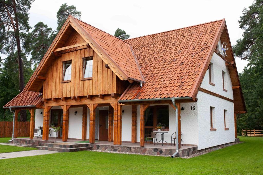 a house with a wooden roof on a yard at Mazurska Gajówka in Ruciane-Nida