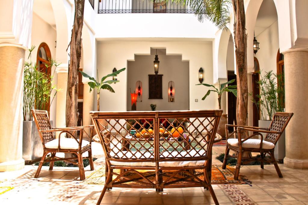 2 stoelen en een tafel in een kamer met palmbomen bij Riad Mariana in Marrakesh