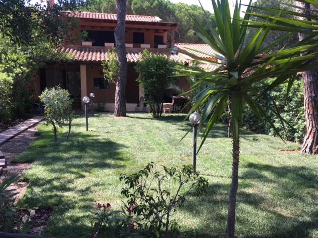 een tuin met een huis en een palmboom bij Villa Calaverde Santa Margherita di Pula in Fort Village