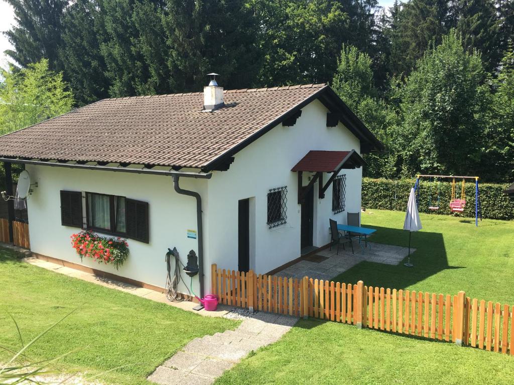 una pequeña casa blanca con una valla en un patio en Ferienbungalow Weber, en Velden am Wörthersee