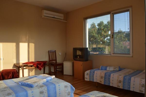 a bedroom with two beds and a tv and a window at Къща за гости "Черната роза" in Bŭlgarevo