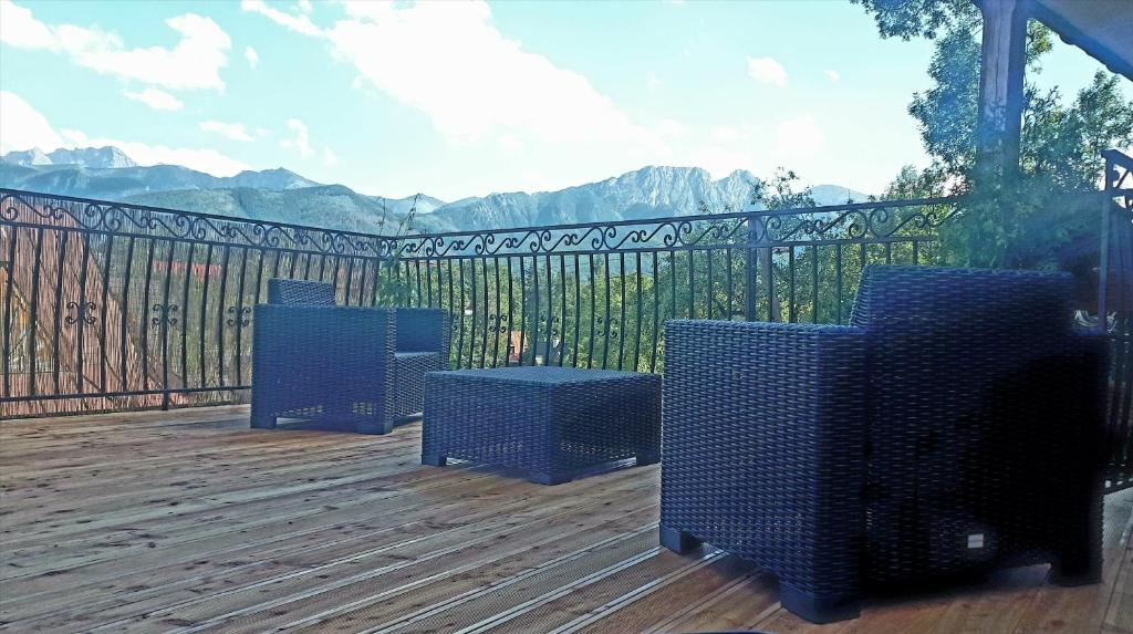 une terrasse avec trois chaises, une table et une clôture dans l'établissement Willa Widokowa Zakopane, à Zakopane