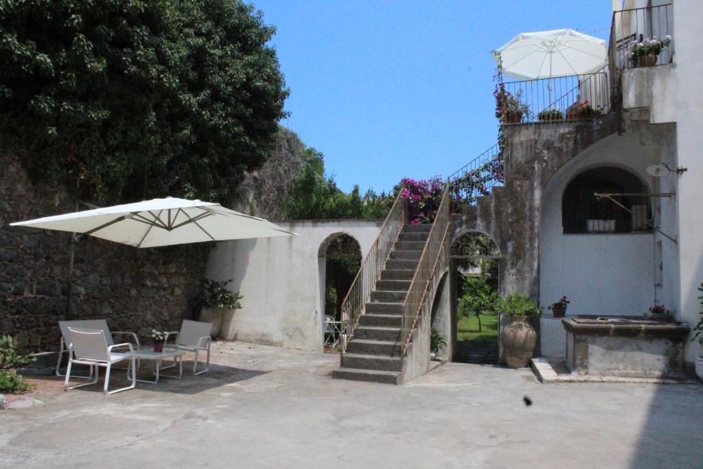 un patio con sombrilla, mesa y escalera en La Corte di Aci, en Acireale