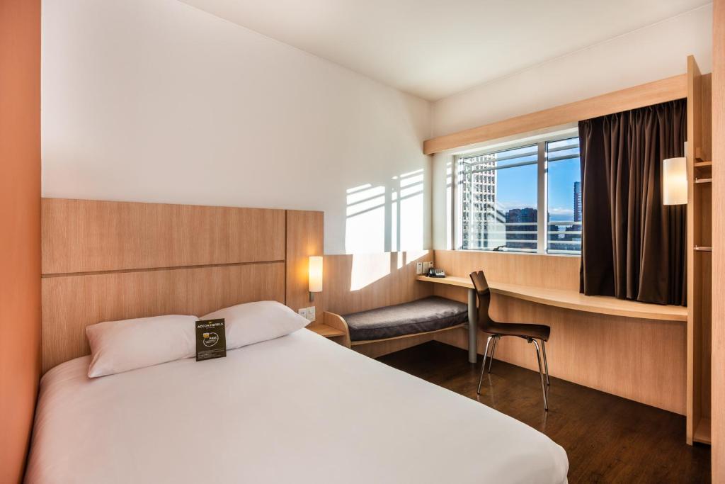 ボゴタにあるibis Bogota Museoのベッド、デスク、窓が備わるホテルルームです。