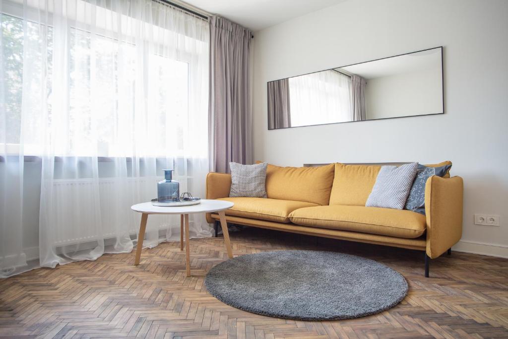a living room with a yellow couch and a table at Downtown Apartment Rentals 2 in Šiauliai