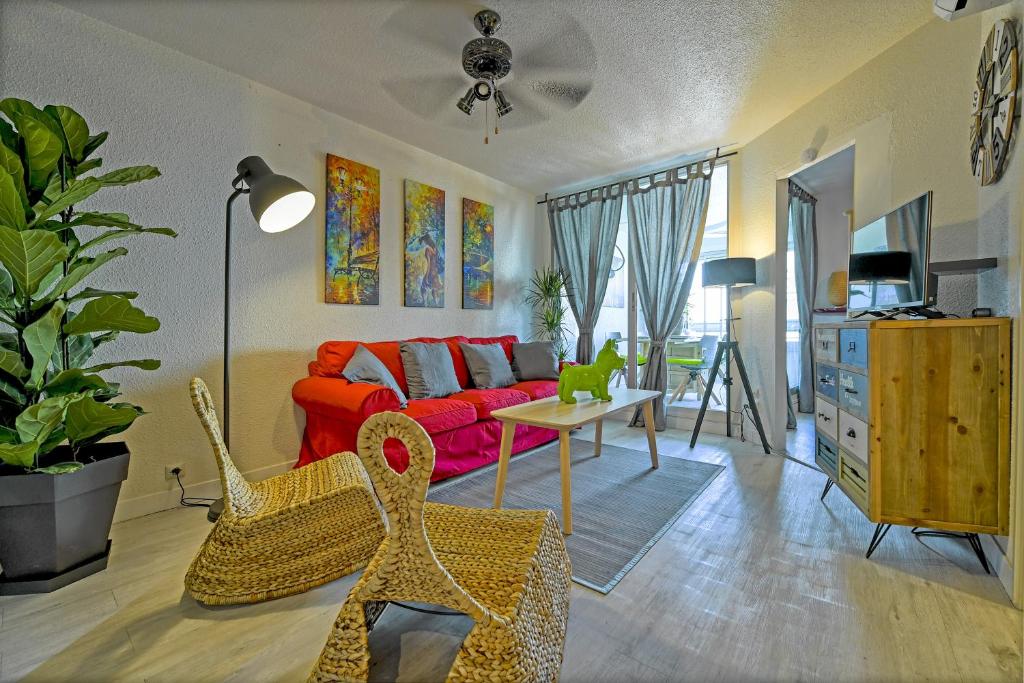 a living room with a red couch and a table at T2 cosy de 41m2 à 400 m de la plage, résidence avec piscine. in Le Grau-du-Roi