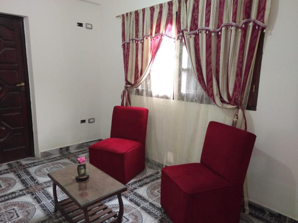 a living room with two red chairs and a table at Bajo la viña in San Salvador de Jujuy