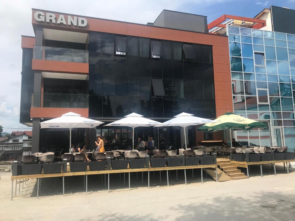 a restaurant with tables and umbrellas in front of a building at Motel Grand in Velika Kladuša
