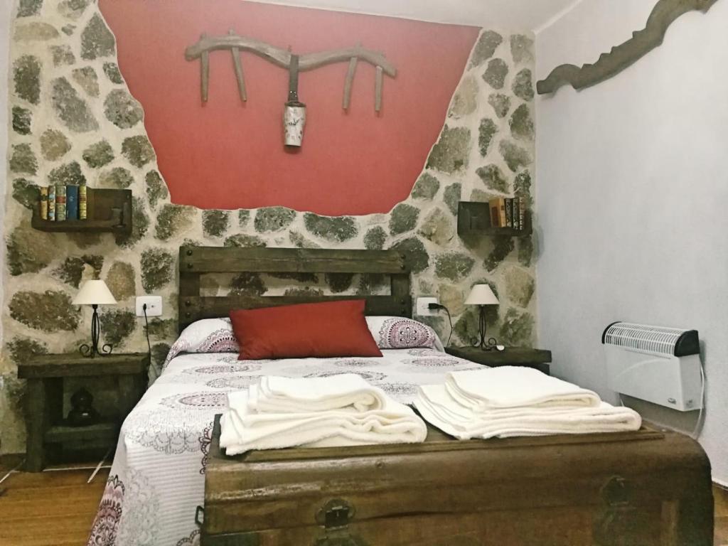 a bedroom with a bed and a red wall at Casa Rural La Presa in Valdeobispo