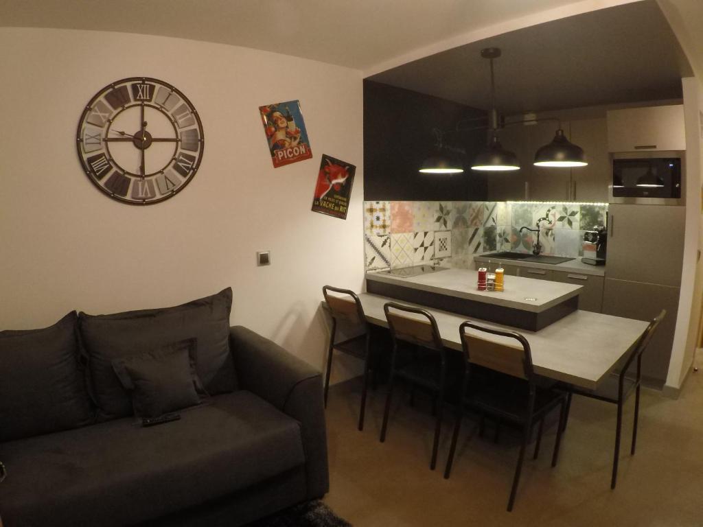 a living room with a table and a clock on the wall at Le Plein Ciel in Bourg-Saint-Maurice