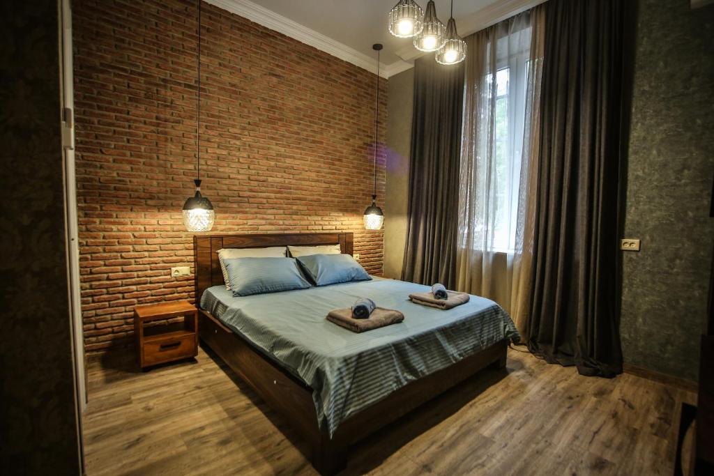 um quarto com uma cama e uma parede de tijolos em Classy Apartments Central em Tbilisi
