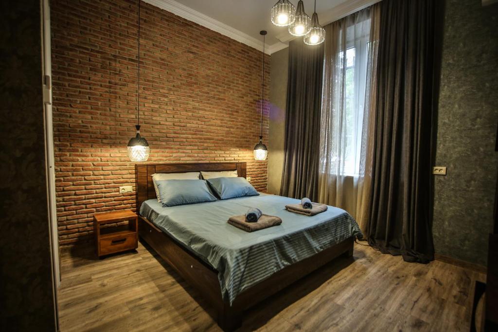 a bedroom with a bed and a brick wall at Classy Apartments Central in Tbilisi City