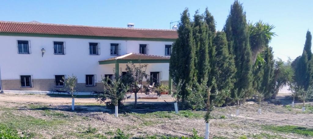 un gran edificio blanco con árboles delante de él en Alojamiento Rural El Orégano, en Campillos