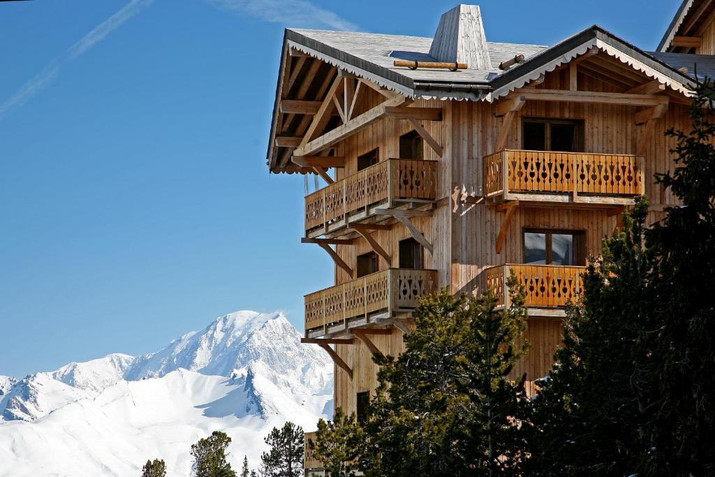 a wooden building with balconies and snow covered mountains at Chalet de l'Ours in Arc 2000