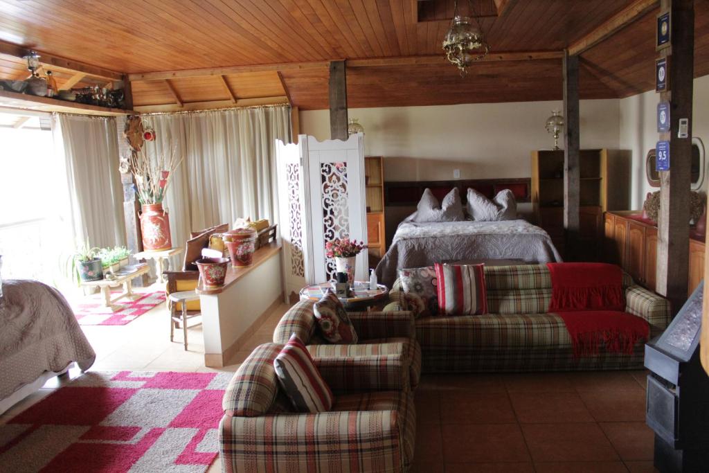 a bedroom with a bed and a couch and chairs at Loft São Joaquim in São Joaquim