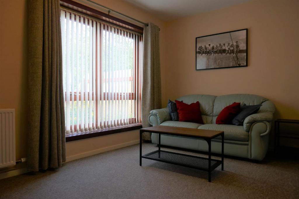 sala de estar con sofá, mesa y ventana en Inverness Family House, en Inverness