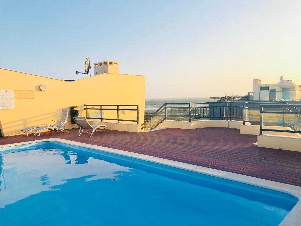 a swimming pool on a deck with the ocean in the background at Garça Real in Olhão
