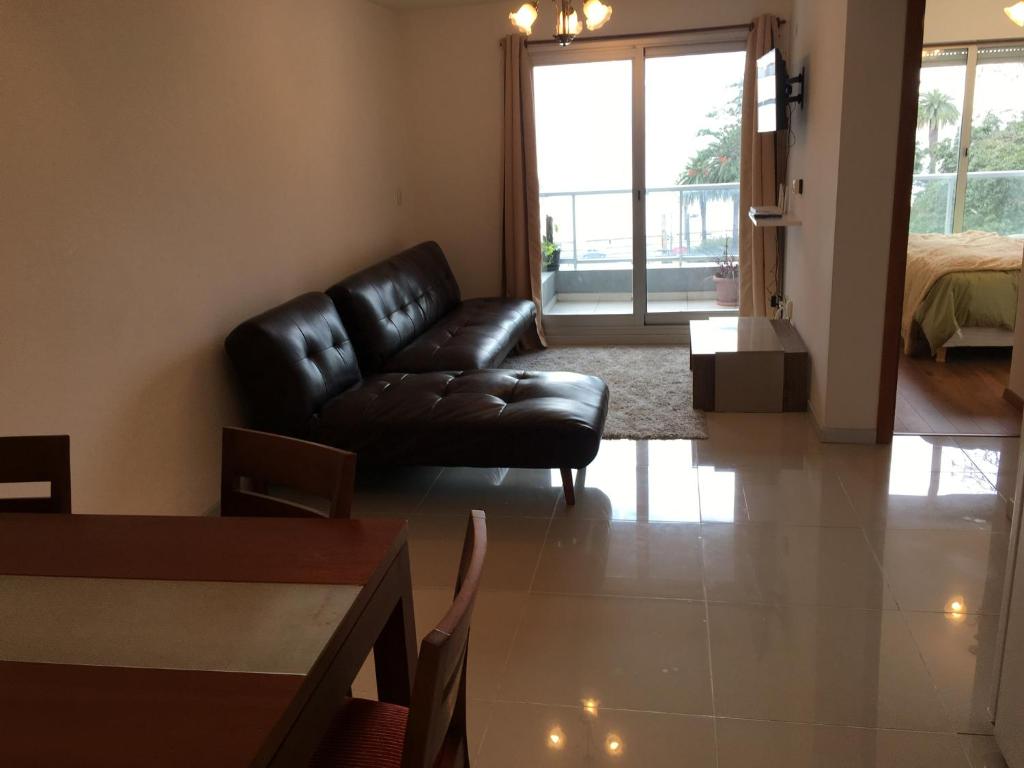 uma sala de estar com um sofá de couro e uma cama em Palm Beach em Montevidéu