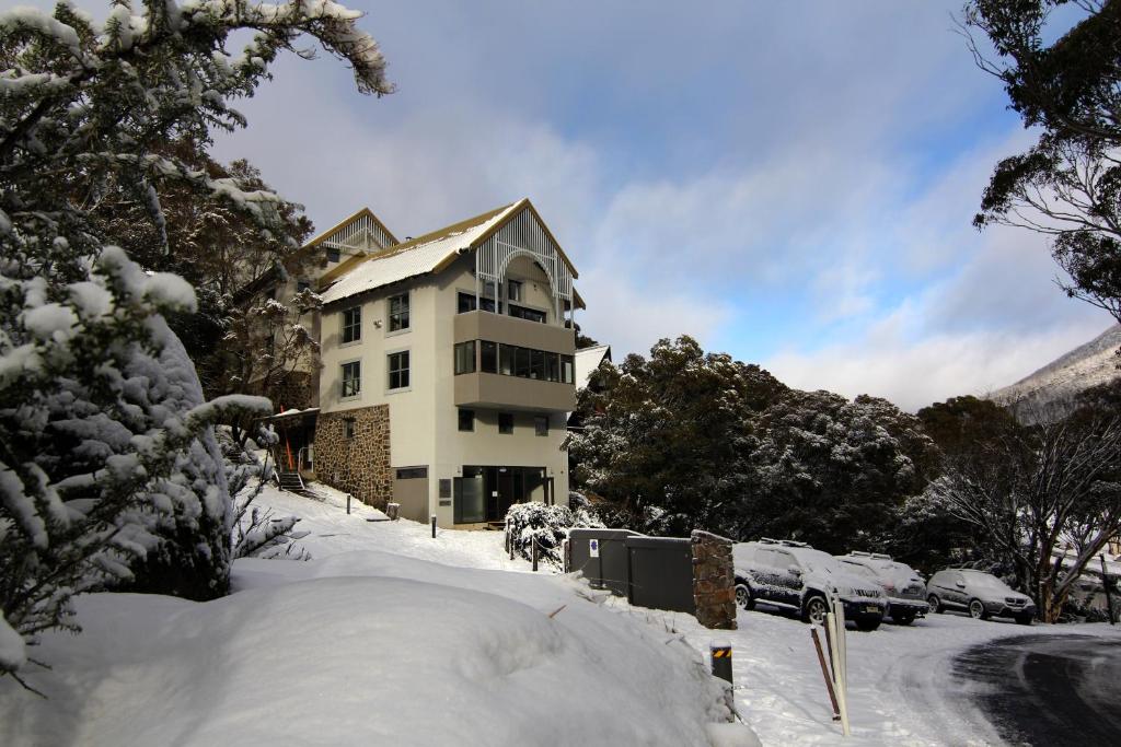 uma casa na neve com carros estacionados na frente em Boali Lodge Thredbo em Thredbo