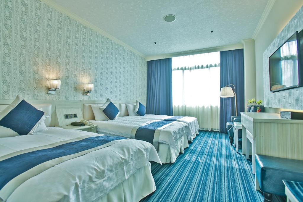 a hotel room with two beds and a window at Hotel River Kinmen in Jincheng