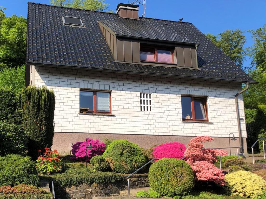 dom z kwitnącymi krzakami przed nim w obiekcie Ferienwohnung am Waldrand mit Dachterrasse w mieście Wetter