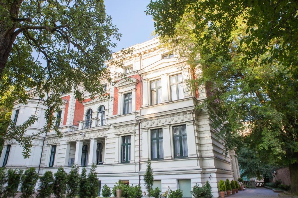 een groot wit gebouw met bomen ervoor bij Matejki 8 in Szczecin