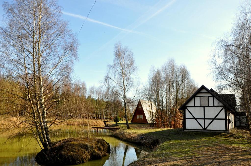 two barns on the side of a river with trees at Agroturystyka "U Sochy" in Ramleje