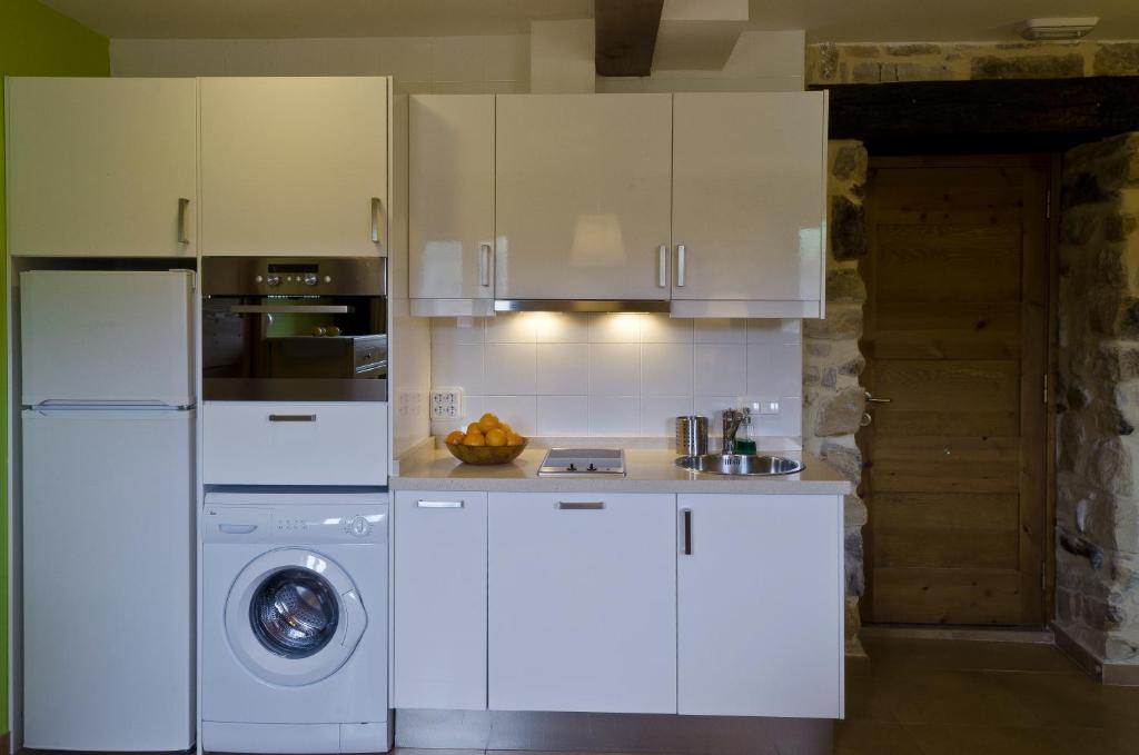 a kitchen with white cabinets and a washing machine at Apartamentos Playa Galizano in Galizano