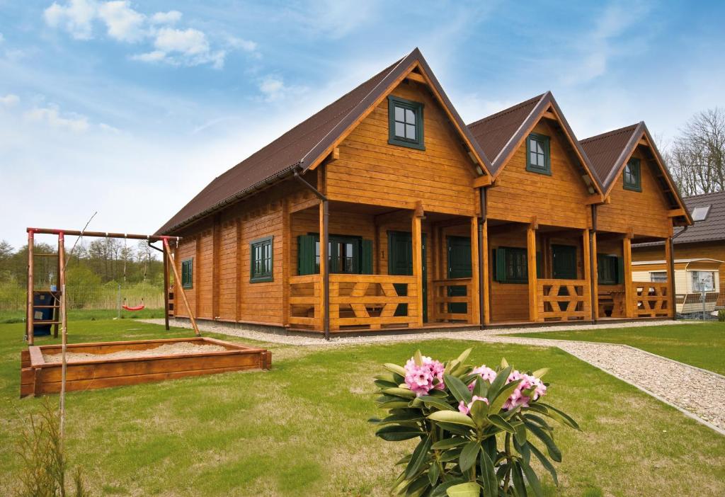 a large wooden house with a yard at Domki letniskowe Słoneczna Zatoka in Sarbinowo