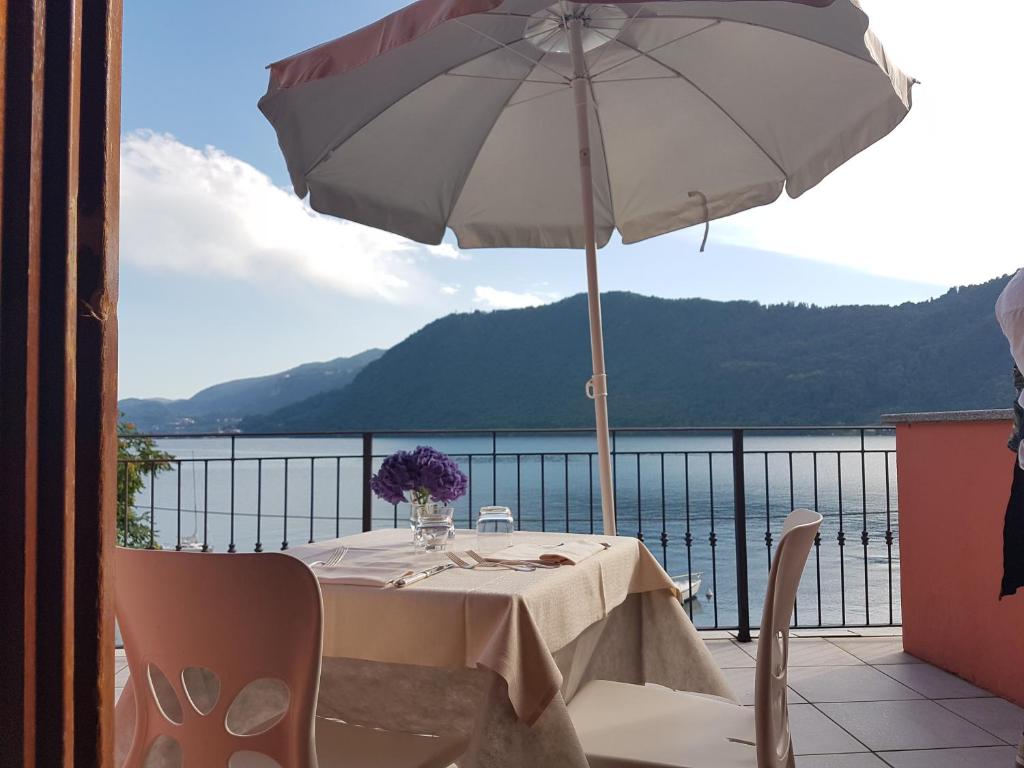a table with an umbrella on a balcony at Hotel & Residence La Sibilla Cusiana in Pettenasco