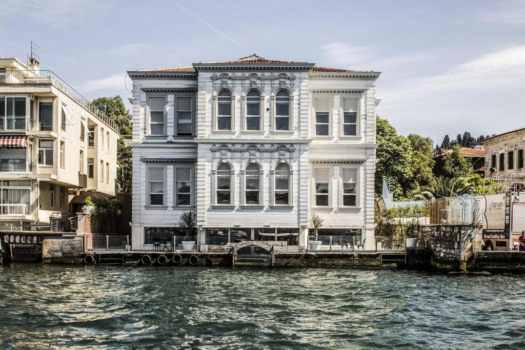 un grande edificio bianco sull'acqua accanto agli edifici di Bosphorus Palace Hotel a Istanbul