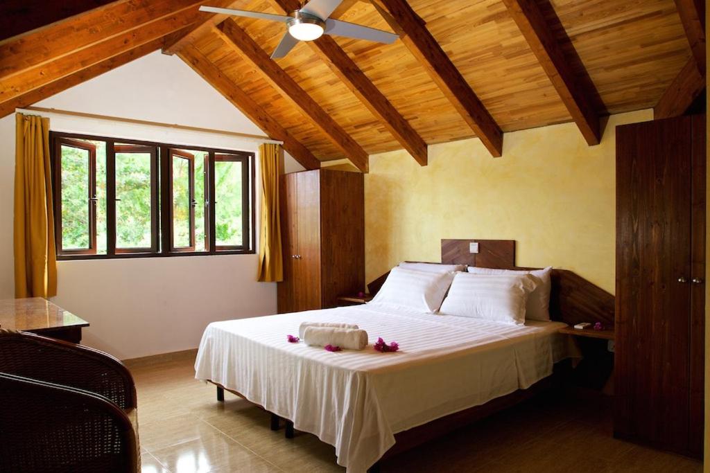 a bedroom with a large bed with a ceiling fan at Villa Sole in Anse Volbert Village